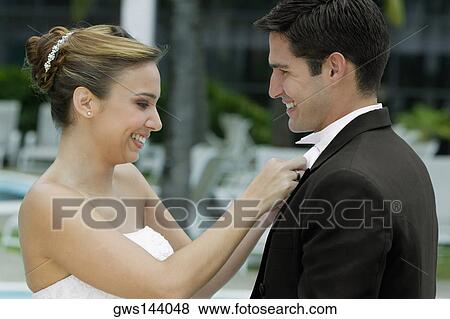 Side profile of a bride adjusting her groom's bow tie View Large Photo Image Stock Photo - Side profile of a bride adjusting her groom's bow tie. Fotosearch