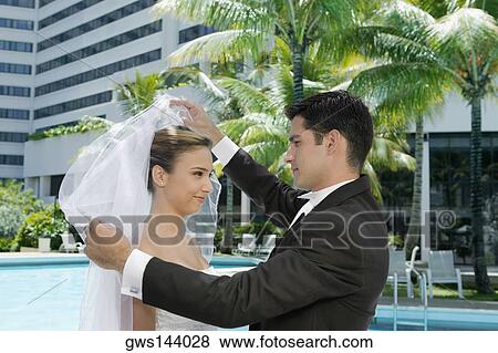 Stock Photo - Side profile of a groom lifting his bride's veil. Fotosearch