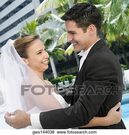 Side profile of a newlywed couple embracing each other View Large Photo Image Stock Photo - Side profile of a newlywed couple embracing each other. Fotosearch