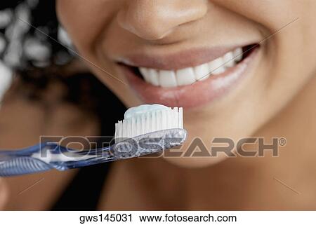 Close-up of a toothbrush with toothpaste in front of a young woman's mouth View Large Photo Image Stock Image - Close-up of a toothbrush with toothpaste in front of a young woman's mouth. Fotosearch