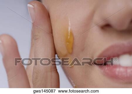 Close-up of a woman applying honey on her cheek View Large Photo Image Stock Photo - Close-up of a woman applying honey on her cheek. Fotosearch