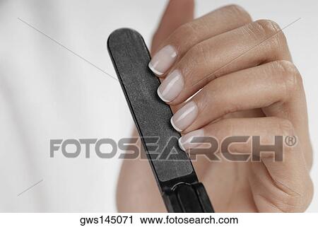 Stock Image - Close-up of a woman's hand filing her nails. Fotosearch