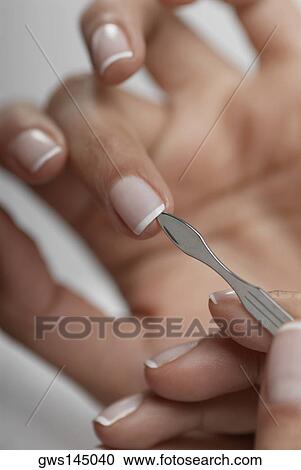 Stock Image - Close-up of a woman's hand giving herself a manicure. Fotosearch