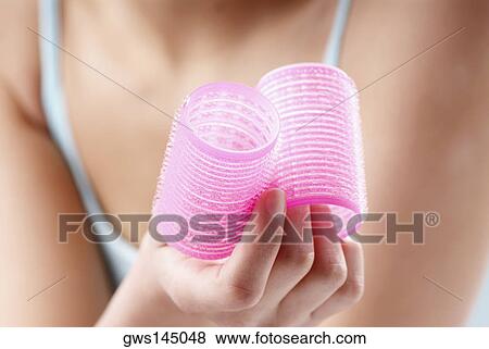 Stock Photo - Close-up of a woman's hand holding curlers. Fotosearch