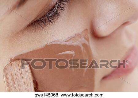 Close-up of a young woman applying a facial mask View Large Photo Image Stock Photo - Close-up of a young woman applying a facial mask. Fotosearch