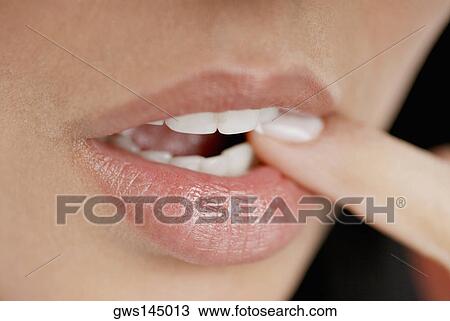 Stock Image - Close-up of a young woman biting her finger. Fotosearch