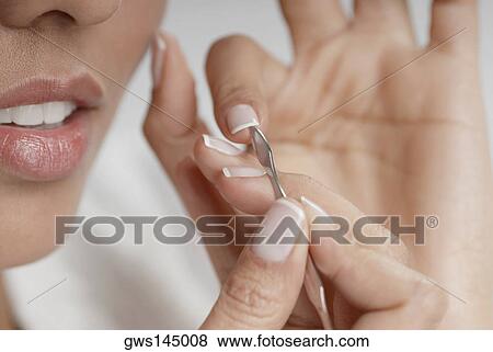 Close-up of a young woman cleaning her fingernails View Large Photo Image Stock Photo - Close-up of a young woman cleaning her fingernails. Fotosearch