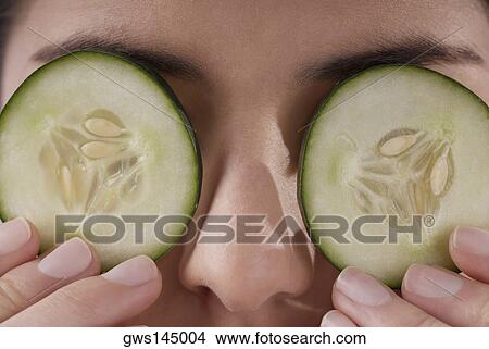 Close-up of a young woman covering her eyes with cucumber slices View Large Photo Image Picture - Close-up of a young woman covering her eyes with cucumber slices. Fotosearch