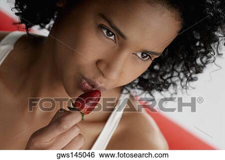 Close-up of a young woman holding a strawberry View Large Photo Image Stock Photograph - Close-up of a young woman holding a strawberry. Fotosearch