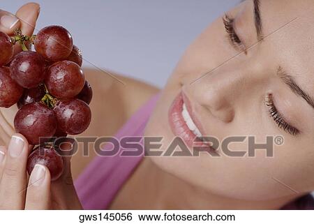 Stock Photograph - Close-up of a young woman holding a bunch of red grapes. Fotosearch