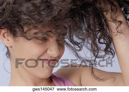 Close-up of a young woman holding her hair and making a face View Large Photo Image Stock Photo - Close-up of a young woman holding her hair and making a face. Fotosearch