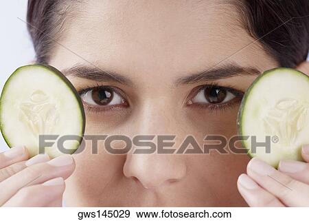 Close-up of a young woman holding two cucumber slices View Large Photo Image Stock Photo - Close-up of a young woman holding two cucumber slices. Fotosearch