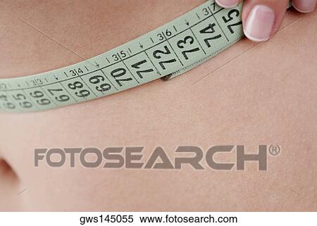 Stock Photography - Close-up of a young woman measuring her abdomen. Fotosearch