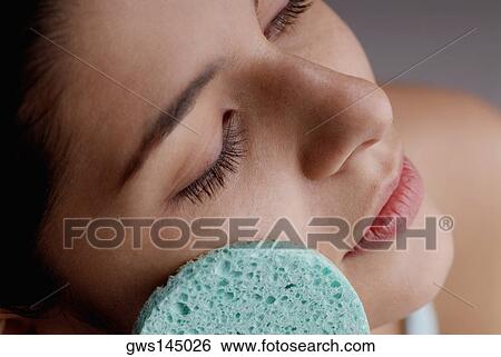 Close-up of a young woman scrubbing her face with a sponge View Large Photo Image Stock Photograph - Close-up of a young woman scrubbing her face with a sponge. Fotosearch