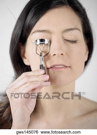Close-up of a young woman using an eyelash curler View Large Photo Image Stock Photograph - Close-up of a young woman using an eyelash curler. Fotosearch