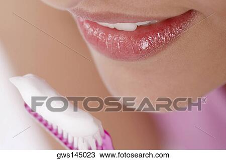 Stock Image - Close-up of a young woman with a toothbrush in front of her mouth. Fotosearch