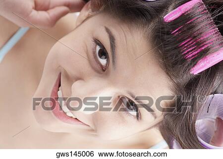 High angle view of a young woman putting on hair curlers and smiling View Large Photo Image Stock Photograph - High angle view of a young woman putting on hair curlers and smiling. Fotosearch