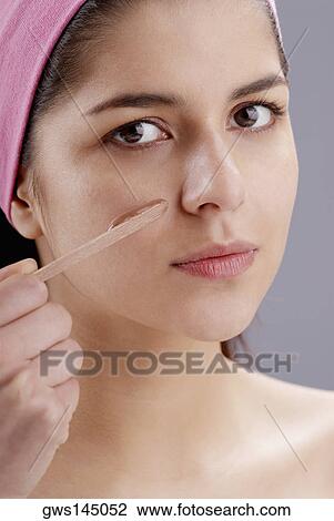 Portrait of a young woman applying a facial mask View Large Photo Image Stock Image - Portrait of a young woman applying a facial mask. Fotosearch