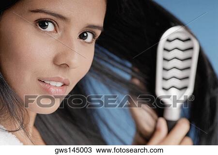 Portrait of a young woman brushing her hair View Large Photo Image Stock Image - Portrait of a young woman brushing her hair. Fotosearch