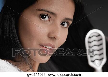 Portrait of a young woman brushing her hair View Large Photo Image Stock Photograph - Portrait of a young woman brushing her hair. Fotosearch