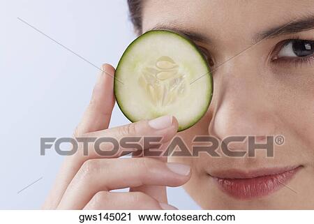 Portrait of a young woman covering her eye with a cucumber slice View Large Photo Image Stock Image - Portrait of a young woman covering her eye with a cucumber slice. Fotosearch