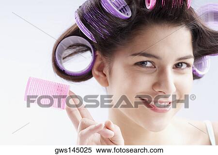 Portrait of a young woman holding a hair curler View Large Photo Image Stock Photography - Portrait of a young woman holding a hair curler. Fotosearch