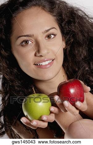 Stock Image - Portrait of a young woman holding two apples. Fotosearch