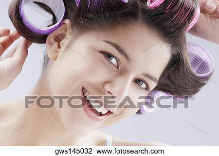 Portrait of a young woman putting curlers in her hair View Large Photo Image Stock Image - Portrait of a young woman putting curlers in her hair. Fotosearch