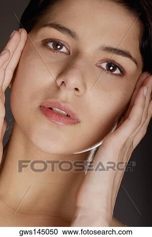 Portrait of a young woman with her hands on her head View Large Photo Image Stock Image - Portrait of a young woman with her hands on her head. Fotosearch