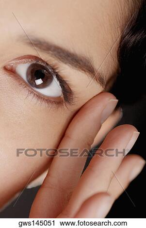 Portrait of a young woman with her fingers near her eye View Large Photo Image Stock Image - Portrait of a young woman with her fingers near her eye. Fotosearch