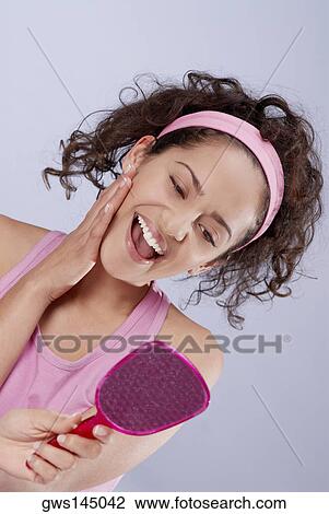Young woman looking into a vanity mirror and laughing View Large Photo Image Stock Image - Young woman looking into a vanity mirror and laughing. Fotosearch