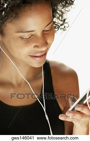 Close-up of a young woman listening to an MP3 player View Large Photo Image Stock Image - Close-up of a young woman listening to an MP3 player. Fotosearch