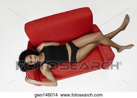 Picture - High angle view of a young woman lying on a couch. Fotosearch