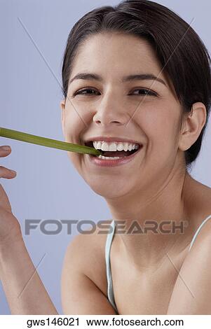 Portrait of a young woman biting into a celery stick and smiling View Large Photo Image Stock Image - Portrait of a young woman biting into a celery stick and smiling. Fotosearch