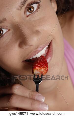 Portrait of a young woman biting into a strawberry with a fork View Large Photo Image Stock Image - Portrait of a young woman biting into a strawberry with a fork. Fotosearch