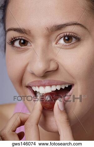 Portrait of a young woman eating a red grape View Large Photo Image Picture - Portrait of a young woman eating a red grape. Fotosearch