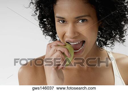 Portrait of a young woman eating an apple View Large Photo Image Stock Photo - Portrait of a young woman eating an apple. Fotosearch