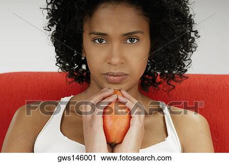 Stock Image - Portrait of a young woman holding a mango. Fotosearch