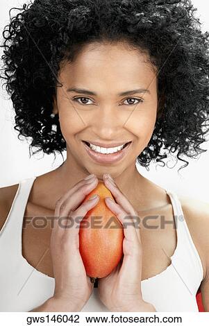 Portrait of a young woman holding a mango and smiling View Large Photo Image Stock Image - Portrait of a young woman holding a mango and smiling. Fotosearch