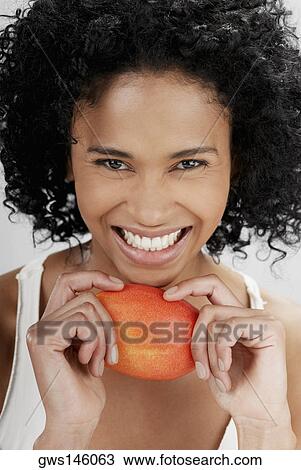 Portrait of a young woman holding a mango and smiling View Large Photo Image Stock Image - Portrait of a young woman holding a mango and smiling. Fotosearch