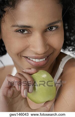 Portrait of a young woman holding an apple and smiling View Large Photo Image Stock Image - Portrait of a young woman holding an apple and smiling. Fotosearch