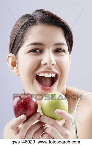 Portrait of a young woman holding two apples View Large Photo Image Stock Photo - Portrait of a young woman holding two apples. Fotosearch