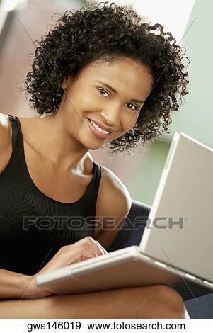 Portrait of a young woman using a laptop View Large Photo Image Stock Photo - Portrait of a young woman using a laptop. Fotosearch
