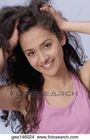 Picture - Portrait of a young woman with her hands in her hair. Fotosearch
