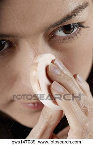 Close-up of a young woman applying face powder with a powder puff View Large Photo Image Stock Photo - Close-up of a young woman applying face powder with a powder puff. Fotosearch