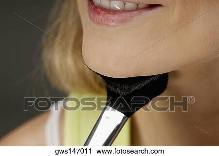 Close-up of a young woman applying make-up with a make-up brush View Large Photo Image Stock Image - Close-up of a young woman applying make-up with a make-up brush. Fotosearch