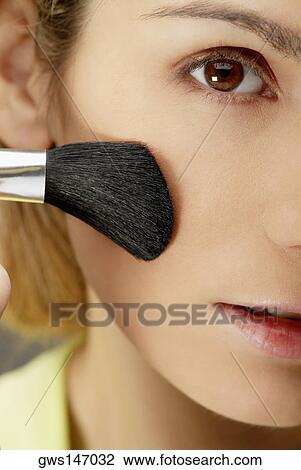 Close-up of a young woman applying make-up with a make-up brush View Large Photo Image Stock Image - Close-up of a young woman applying make-up with a make-up brush. Fotosearch