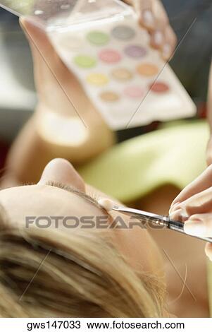 Close-up of a young woman applying eyeshadow View Large Photo Image Stock Image - Close-up of a young woman applying eyeshadow. Fotosearch