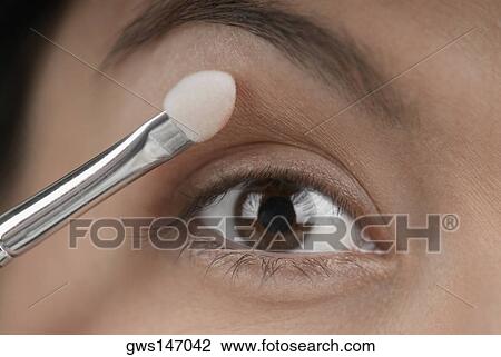 Close-up of a young woman applying eyeshadow View Large Photo Image Stock Image - Close-up of a young woman applying eyeshadow. Fotosearch