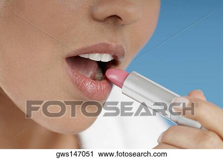Close-up of a young woman applying lipstick View Large Photo Image Stock Image - Close-up of a young woman applying lipstick. Fotosearch